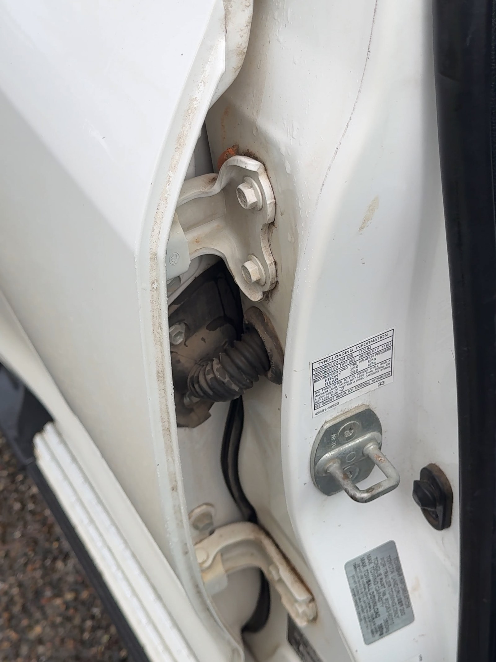 The door shut of a work vehicle before cleaning, grime worked into the hinge and along the seam